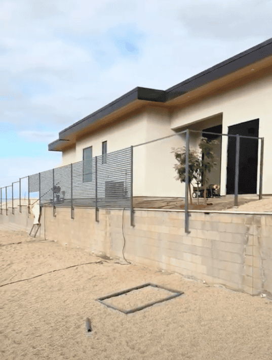 Horizontal steel slat privacy fence wrapping around an elevated modern home.