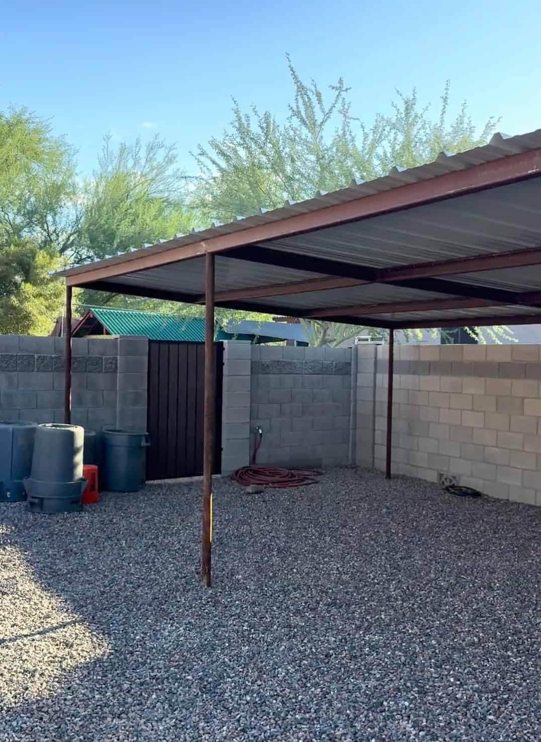 Completed custom pipe shade structure by Mobile METAL Medics with PBR metal roof panels over a gravel outdoor area.