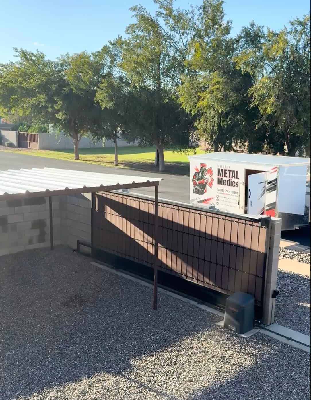 Mobile METAL Medics custom pipe shade structure with PBR metal roof panels and the company trailer visible outside the property.